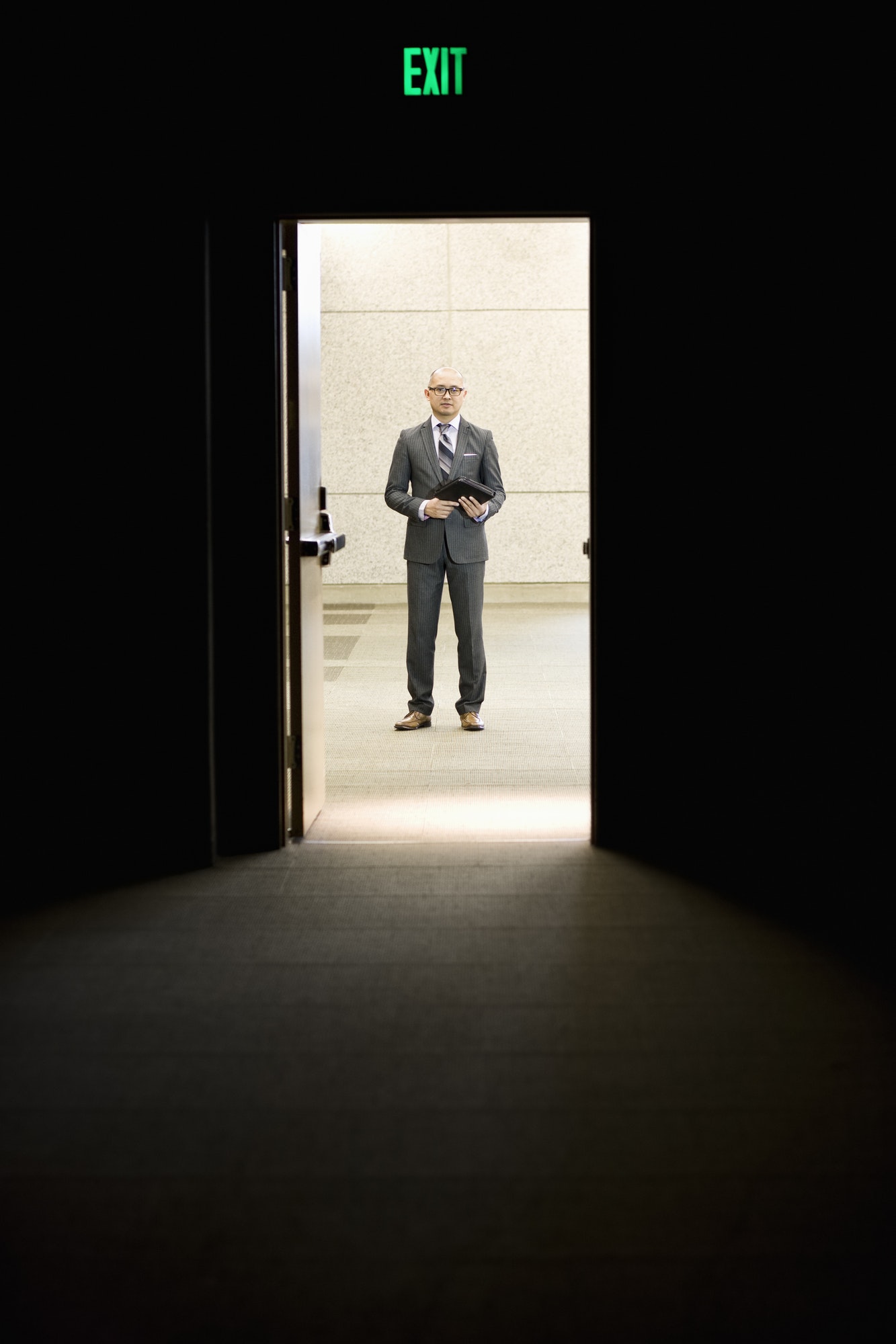 Businessman standing in a doorway between rooms in a convention center arena.