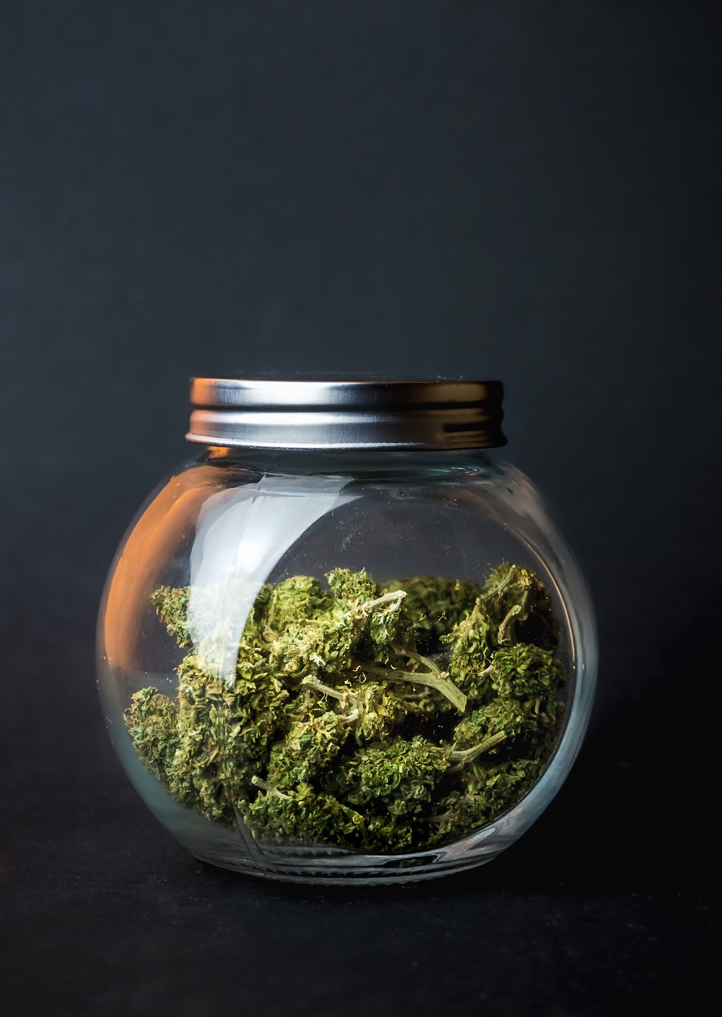 Marijuana flower buds in jar on black background