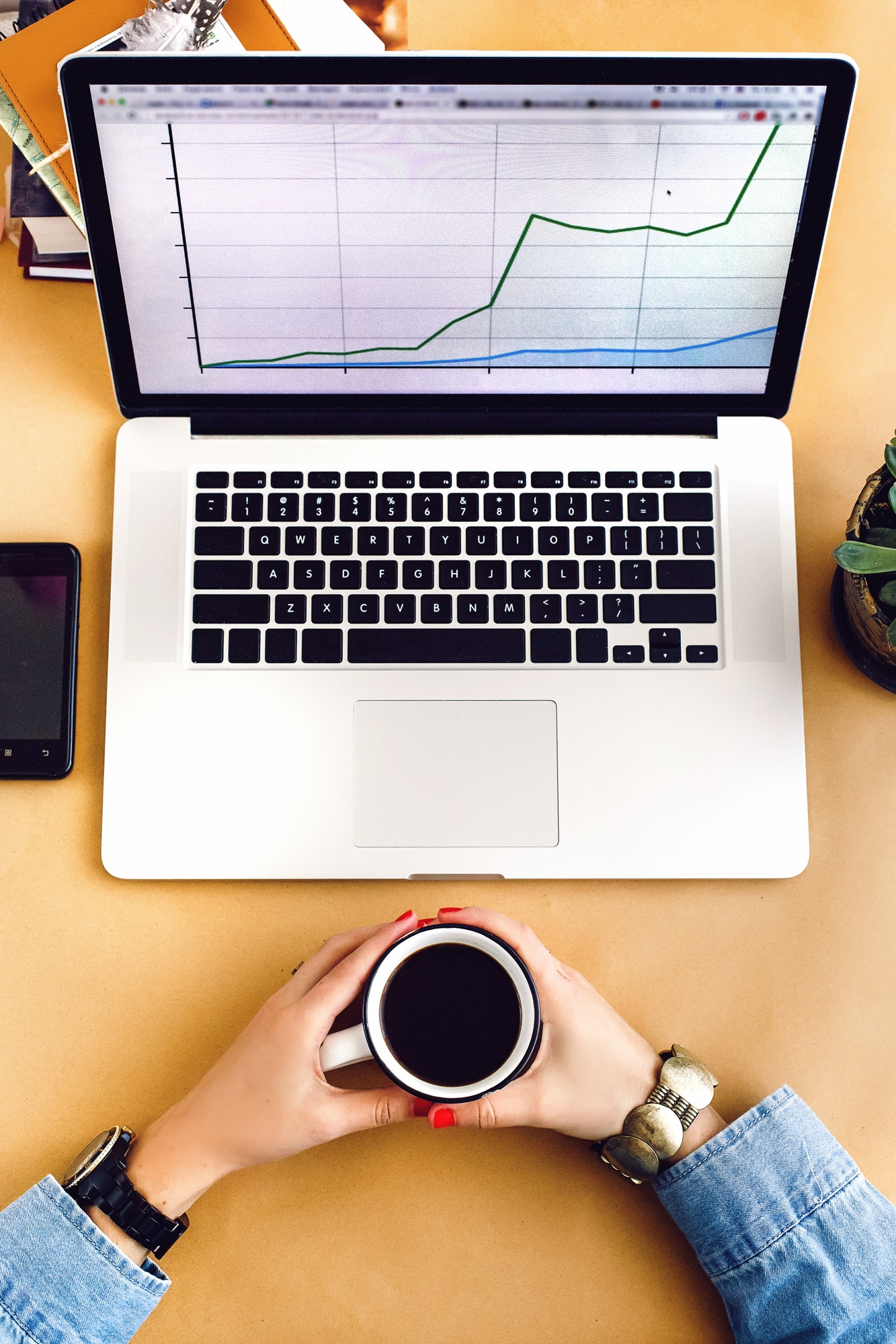 stylish young girl holding cup of coffee with laptop and phone